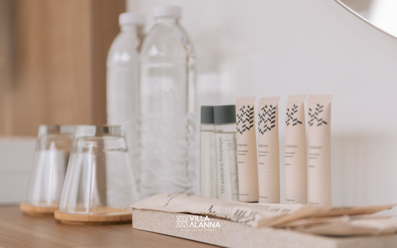 Un baño con tocador de madera, botellas de vidrio transparente y artículos de tocador.