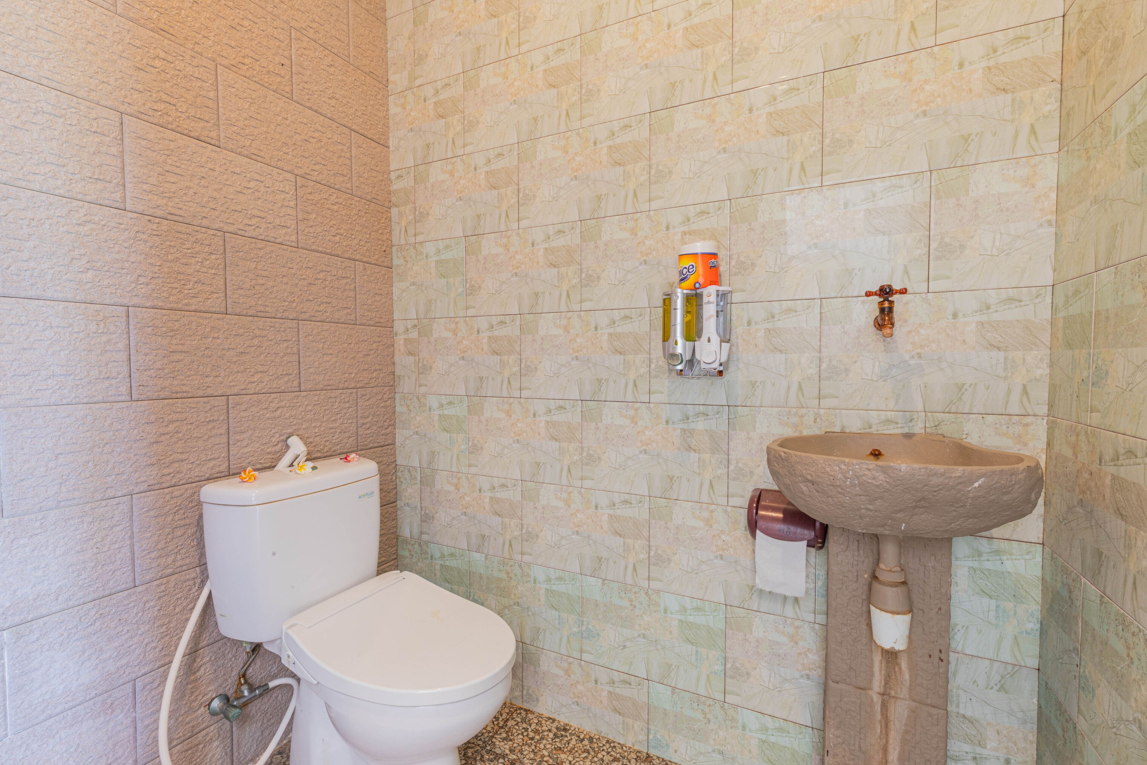 A bathroom with a toilet, a sink, and a wall-mounted dispenser.