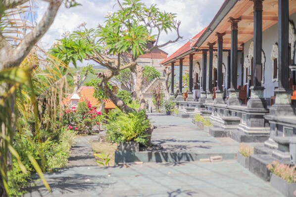 A pathway leading to a traditional building with a tiled roof and columns.