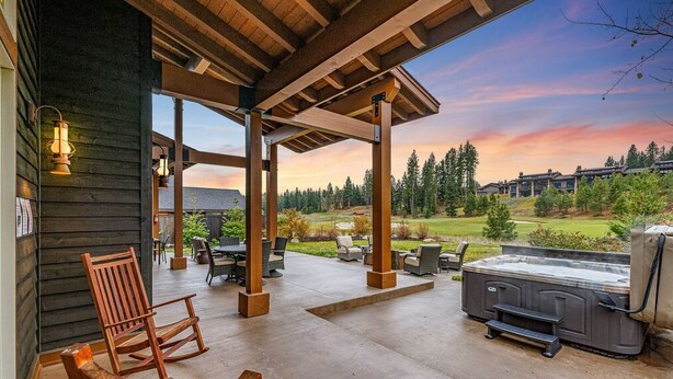 Patio esterno con mobili in legno, vasca idromassaggio e vista su un campo da golf.
