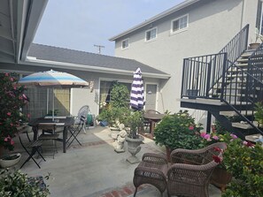 Un patio con mobiliario exterior, una escalera y plantas en macetas.