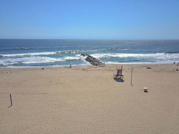 Una playa con una torre de salvavidas, olas y gente.