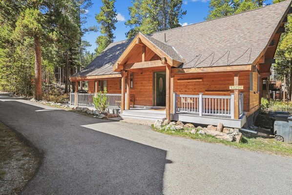 A wooden cabin with a porch and a sign indicating "87 Gold King Parking, Only".