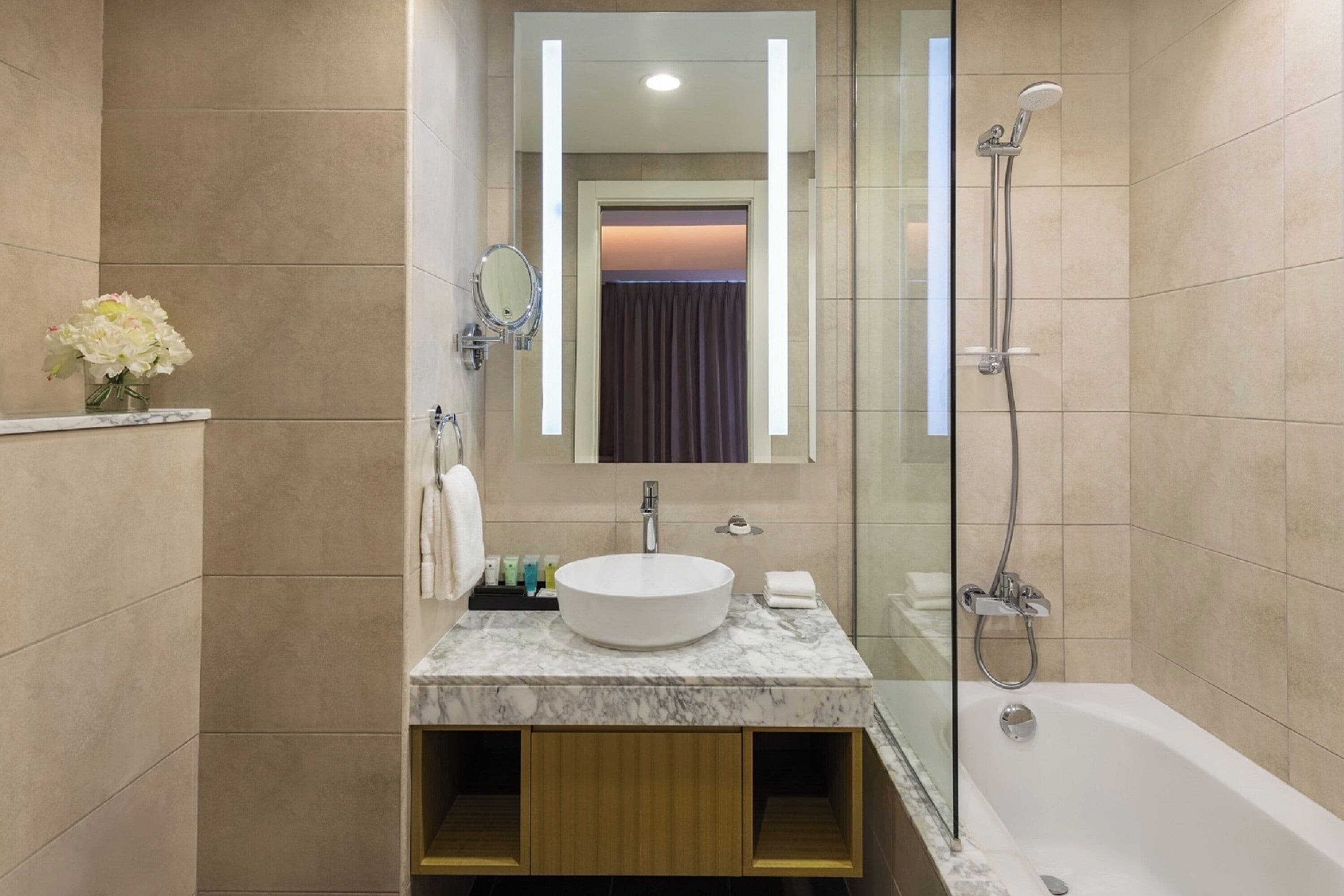 A modern bathroom with a marble sink, a glass-enclosed shower, and a large mirror.