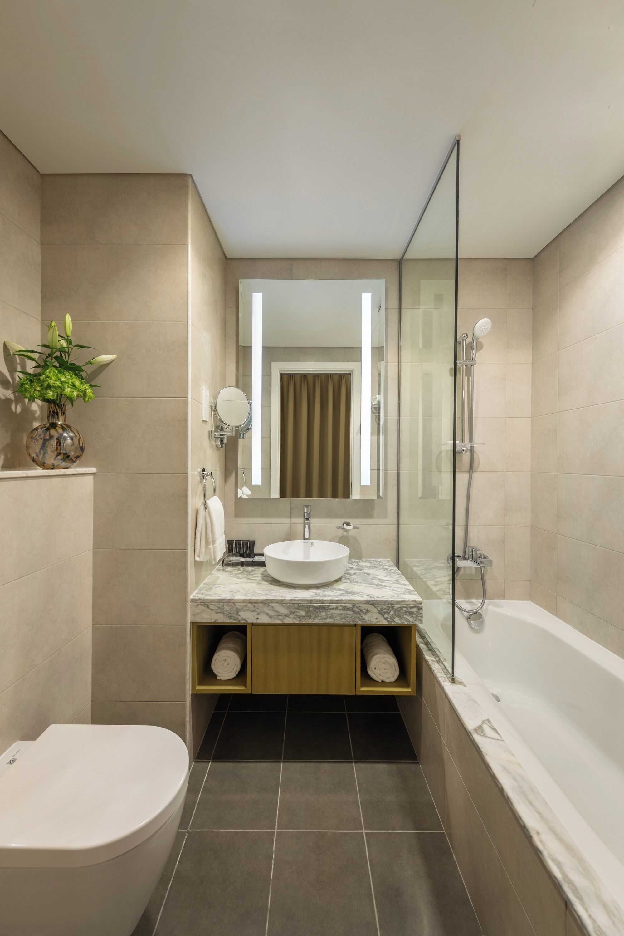 A modern bathroom with a marble sink, a glass-enclosed shower, and a toilet.