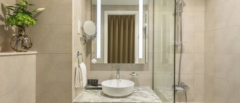 A modern bathroom with a marble sink, a glass-enclosed shower, and a toilet.