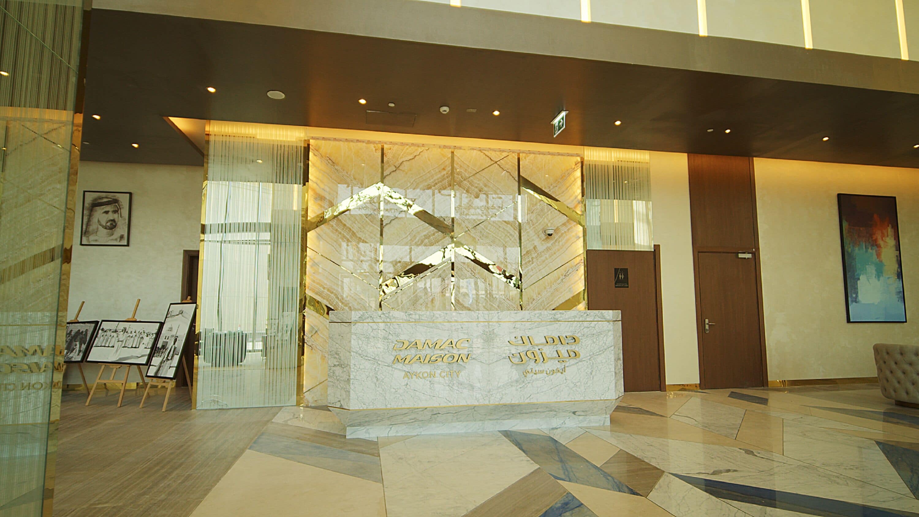 A reception desk with a marble top, a framed portrait on the wall, and a modern chandelier.