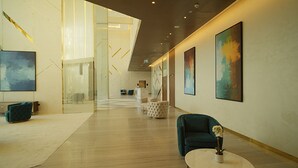 Un hall d’entrée spacieux, doté d’un plafond haut, de meubles modernes et d’œuvres d’art accrochées aux murs.