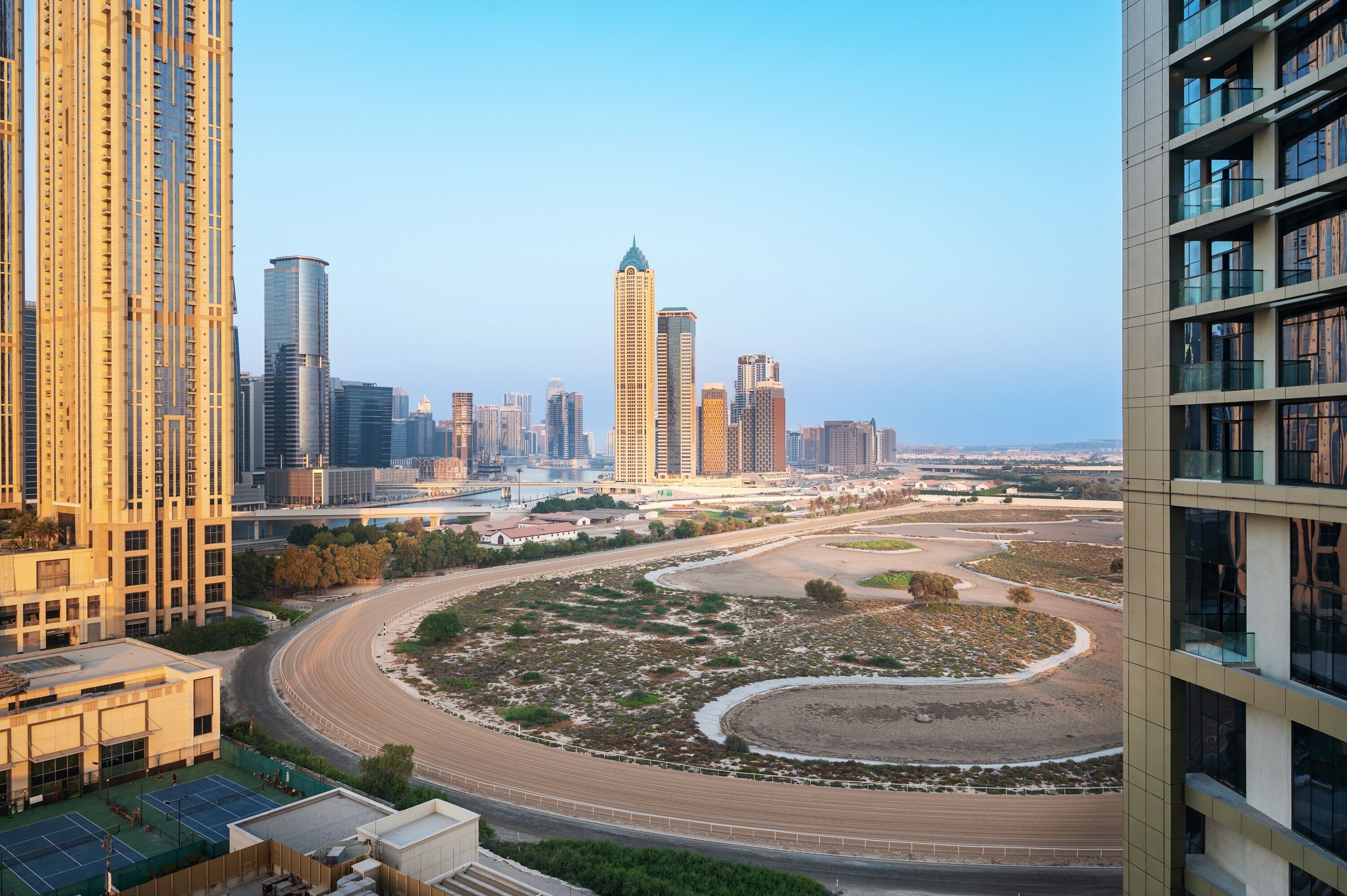 A high-rise building with a modern architectural design, featuring a curved road and a river in the foreground.
