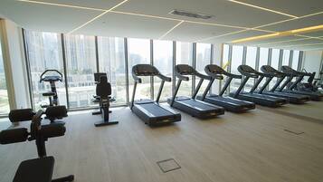 Une salle de sport équipée de tapis de course, d’haltères et d’appareils d’exercice.