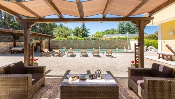 An outdoor patio with wicker furniture, a table set for a meal, and a pergola overhead. - Villa Dosagiri Stanza Privata+piscina (Selva di Fasano)