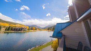 A lakeside view with a building, a clear sky, and autumn foliage.