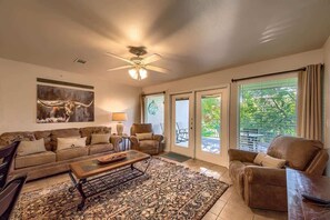 A living room with a sofa, armchairs, a coffee table, and a ceiling fan.