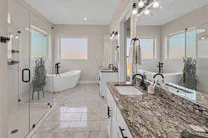 A modern bathroom with a freestanding bathtub, a large vanity with a marble countertop, and a large mirror.