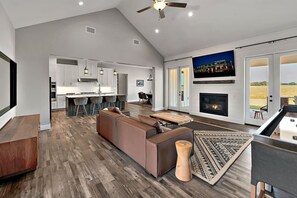 Amplia sala de estar con chimenea, un televisor grande y vistas al exterior.