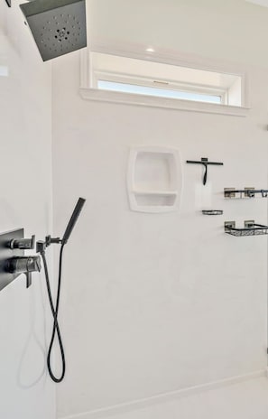 A modern bathroom with a shower, a toilet, and a small window. - New! Luxury Texas Farmhouse (Waco)