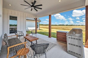 A covered patio with outdoor furniture, a ceiling fan, and a barbecue grill.