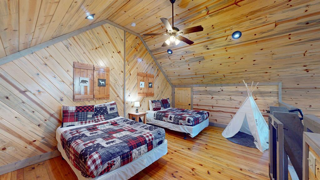 A cozy cabin with two beds, a ceiling fan, and a teepee.