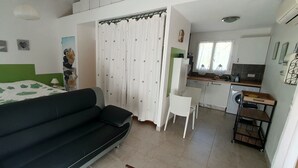 A compact room with a bed, a sofa, a small kitchen area, and a bathroom. - Studio Dans Propriété Avec Piscine au Calme Proche des Gorges du Verdon (Régusse)