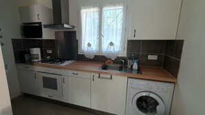 A compact kitchen with a stove, oven, sink, and washing machine. - Studio Dans Propriété Avec Piscine au Calme Proche des Gorges du Verdon (Régusse)