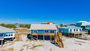 A beachfront property with multiple houses, each featuring a wooden deck and a staircase leading to a beachside platform.