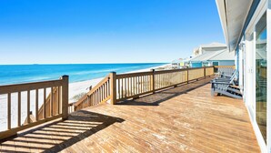 A wooden deck with a view of the beach and ocean.
