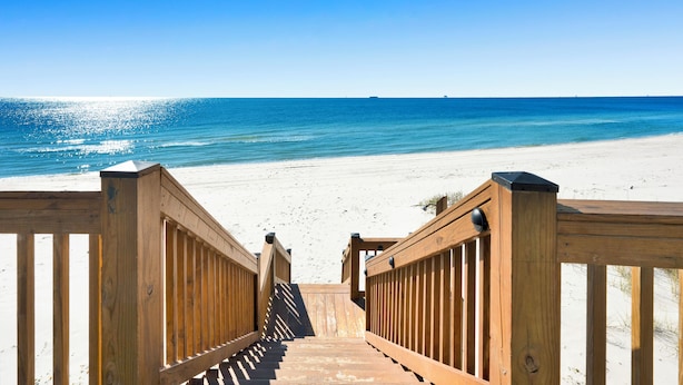A wooden staircase leading to a beach with a clear blue sky.