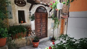 A courtyard with a rustic stone wall, a wooden door, and various potted plants.