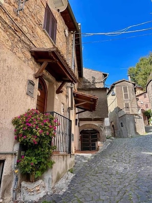 A narrow cobblestone street flanked by historic buildings with stone facades and wooden balconies. - Vrbo Property (Subiaco)