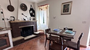 A dining area with a fireplace, a table set for two, and a window with curtains.