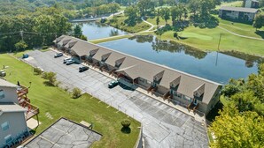 A hotel with a parking lot, a lake, and a golf course in the background.