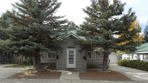 A log cabin with a white door, two windows, and a small porch area.