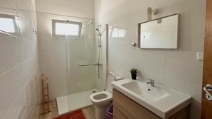 A modern bathroom with a glass-enclosed shower, a toilet, a sink, and a small potted plant. - Anchor House Albufeira (Albufeira)