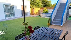 A patio with a wooden table, chairs, a vase with flowers, and a Wi-Fi sign. - Anchor House Albufeira (Albufeira)