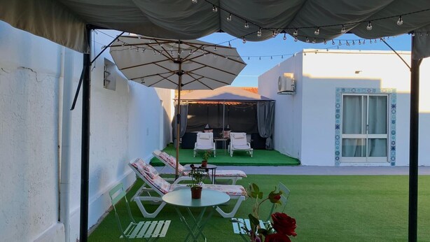 A covered outdoor patio with a table and chairs, a small table with a potted plant, and a decorative rose. - Anchor House Albufeira (Albufeira)