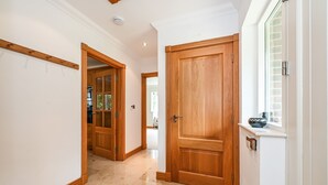 A hallway with wooden doors and a window with blinds. - Woodland Cottage by inspirestays.com - a cottage that sleeps 2 guests in 1 bedroom (Duncton)