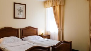 A double bed with a wooden headboard, a bedside table with a lamp, and a framed picture on the wall. - Hotel U Zámečku Cihelny (Karlovy Vary)