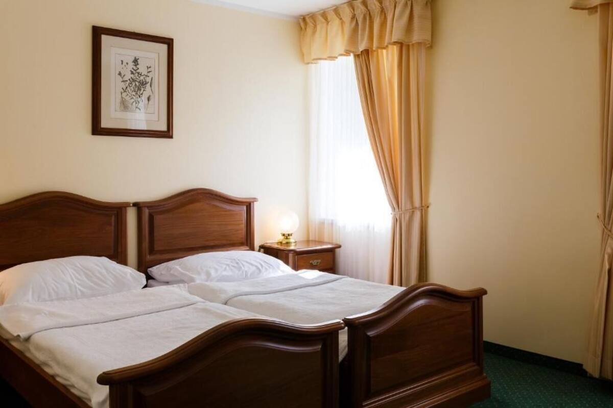 A double bed with a wooden headboard, a bedside table with a lamp, and a framed picture on the wall.