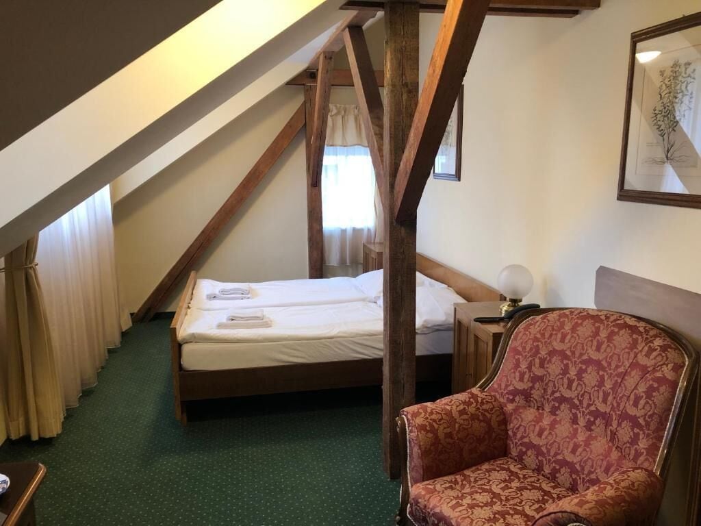 A bedroom with a wooden ceiling, a bed, a chair, and a nightstand.