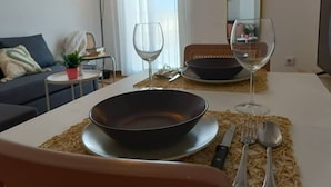 Un comedor con una mesa dispuesta para dos personas, un tazón, copas de vino y cubiertos.