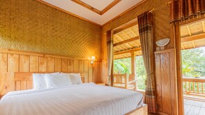 Une pièce en bois avec un lit, une fenêtre avec des rideaux et une vue sur la verdure à l’extérieur.
