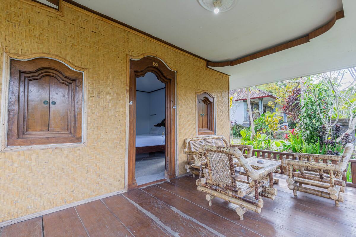 A room with a woven wall, a wooden door, a bed, and a seating area with rattan furniture.