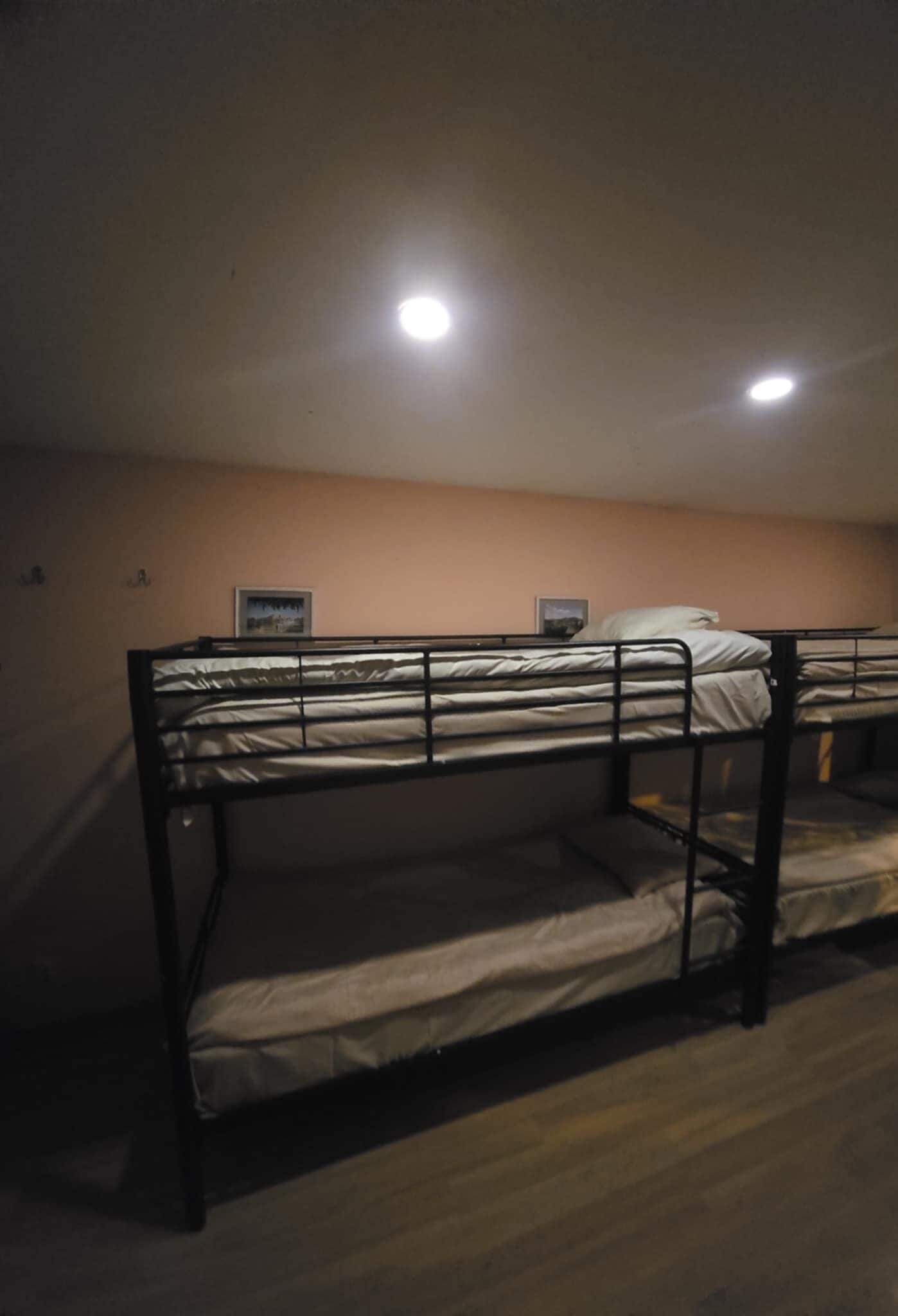 A bunk bed room with two beds, a framed picture on the wall, and a ceiling light.