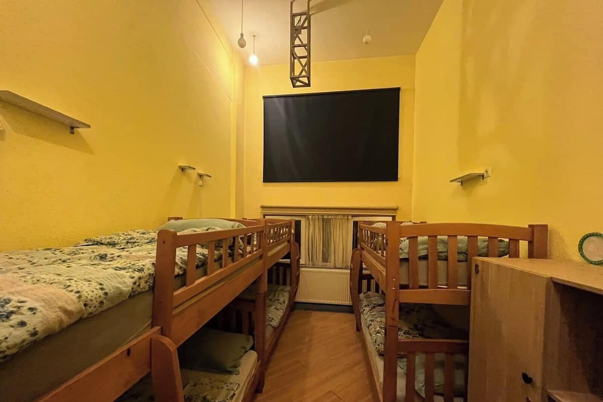 A dormitory room with bunk beds, a blackboard on the wall, and a wooden ladder.