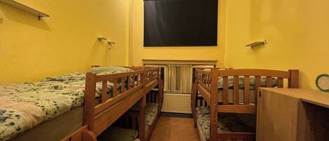 A dormitory room with bunk beds, a blackboard on the wall, and a wooden ladder.