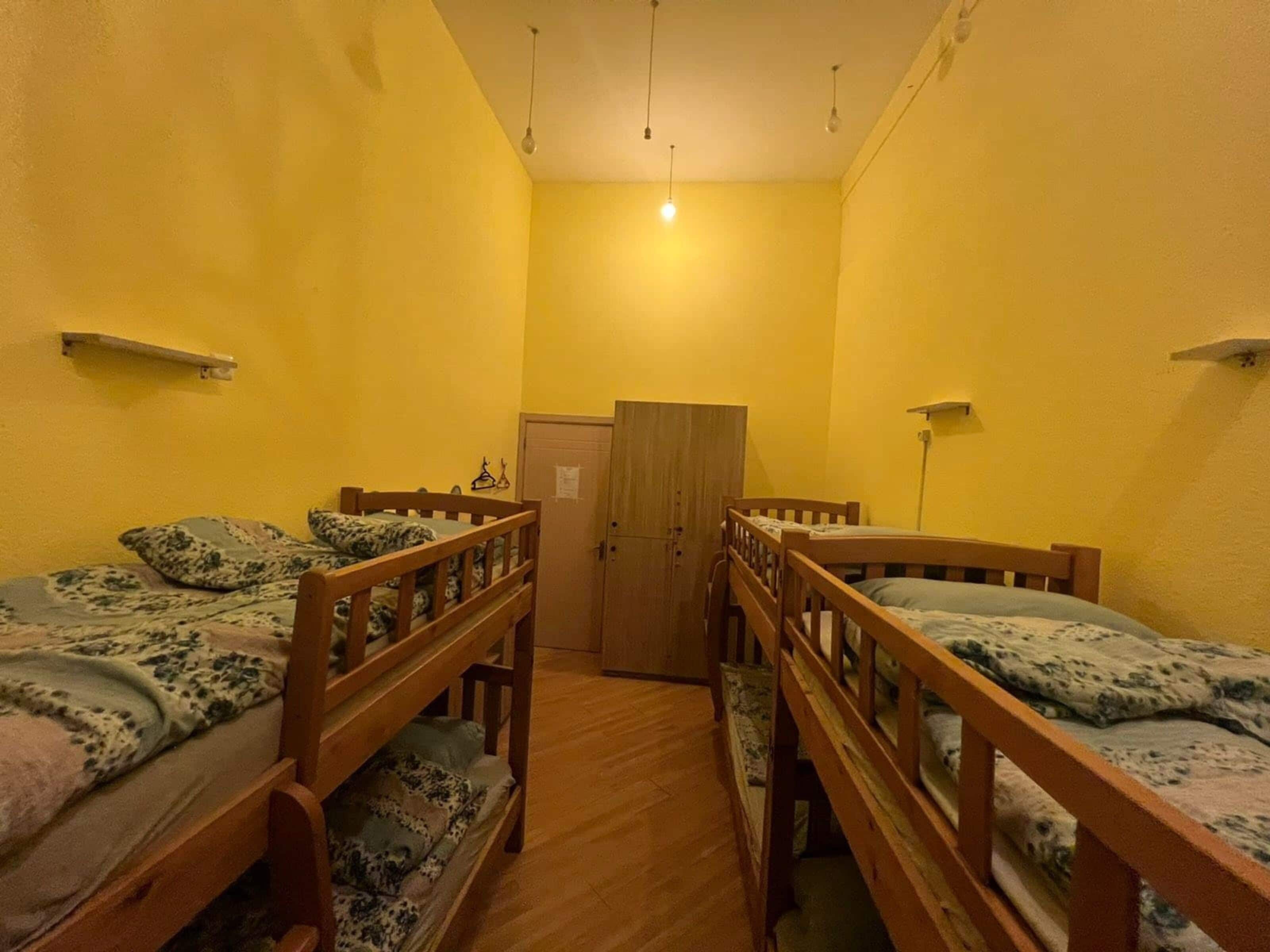 Quarto com duas beliches de madeira, um guarda-roupa de madeira e uma porta.