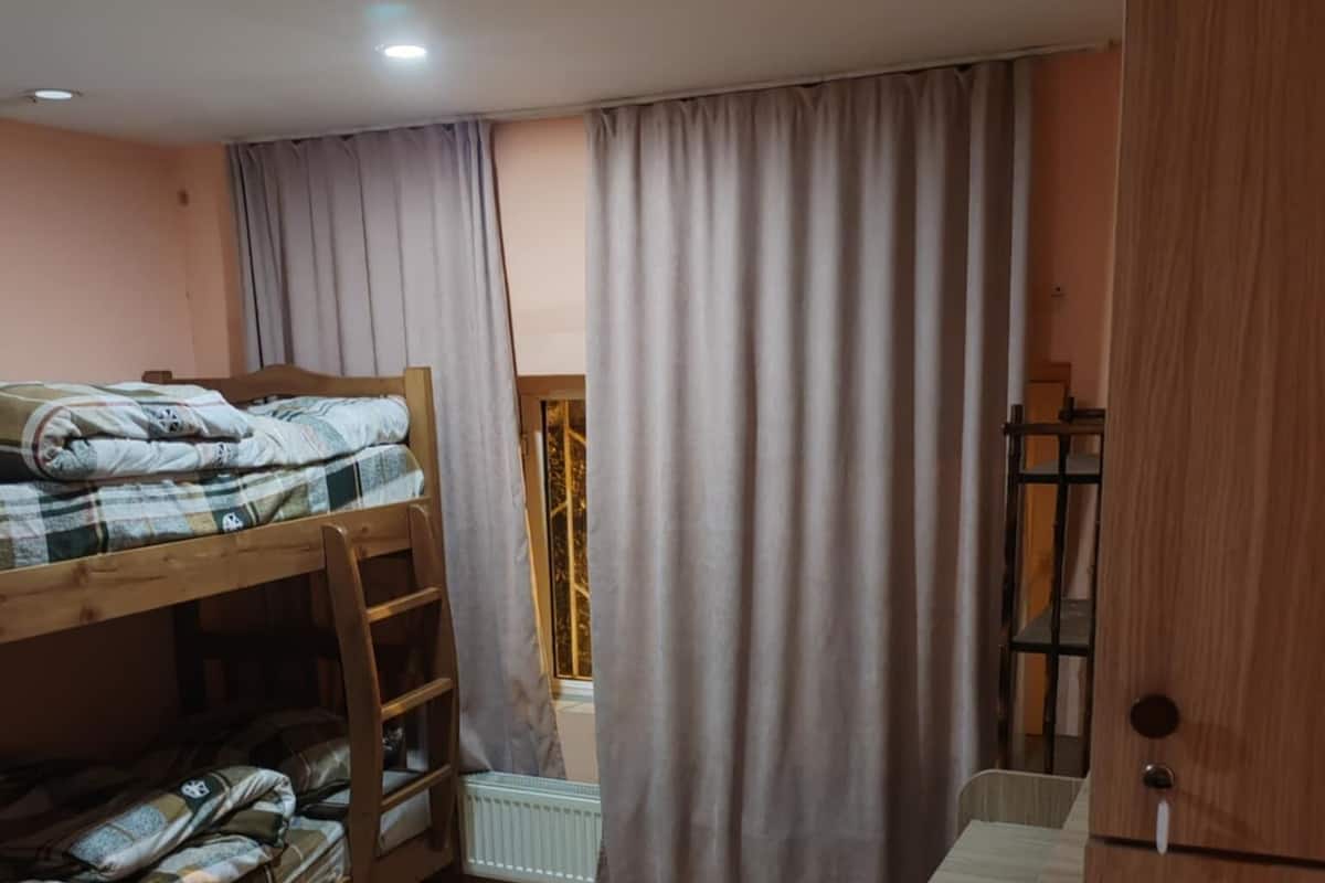 A room with a bunk bed, a wooden wardrobe, and a radiator.