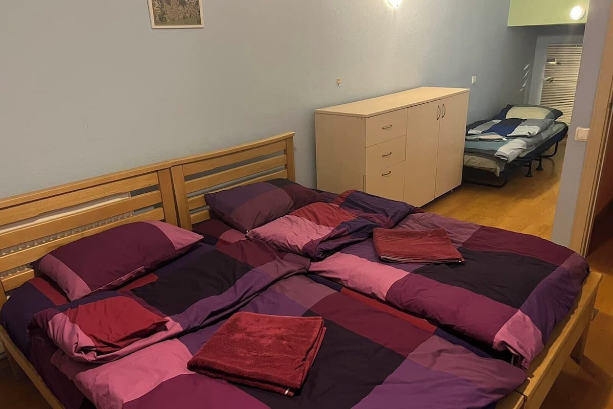 A bedroom with a bed, a wooden headboard, a wardrobe, and a small table with a chair.