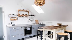Une cuisine moderne avec des meubles de rangement gris, une table en bois et des tabourets de bar.