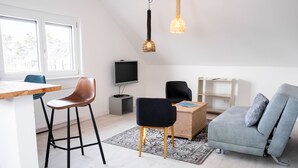 Un salon moderne avec un canapé, deux fauteuils, un téléviseur et une table en bois.